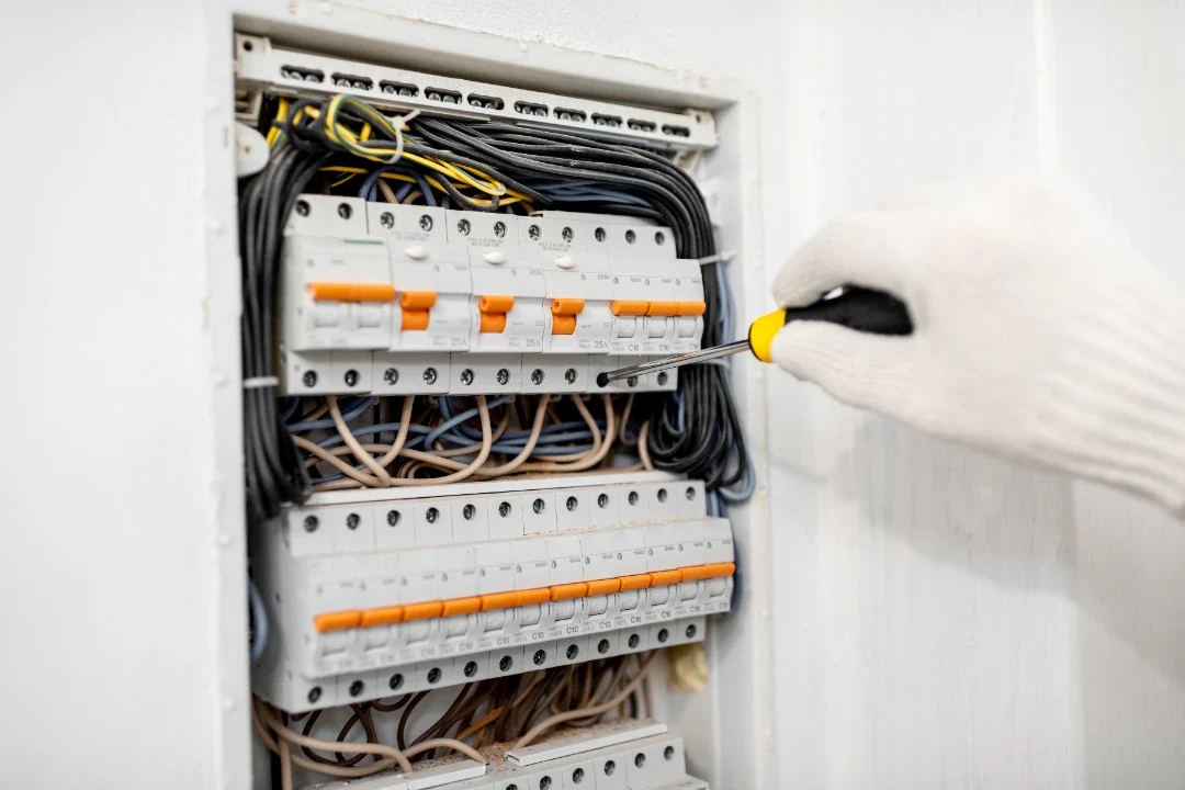 Elektriker arbejder på elskab med værktøj i hjemmet.